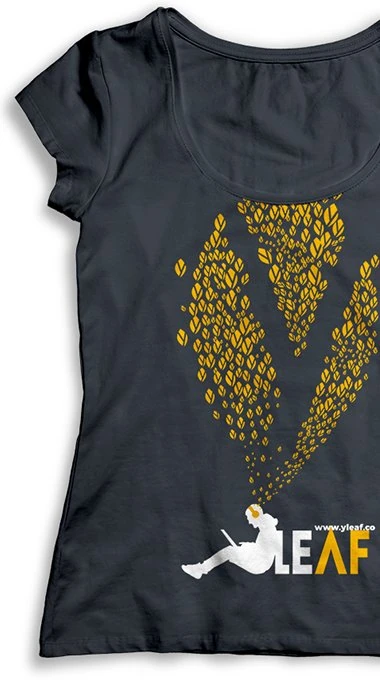 Dark T-shirt with a y made of small yellow leaves above the LEAF wordmark and a person sitting with a laptop
